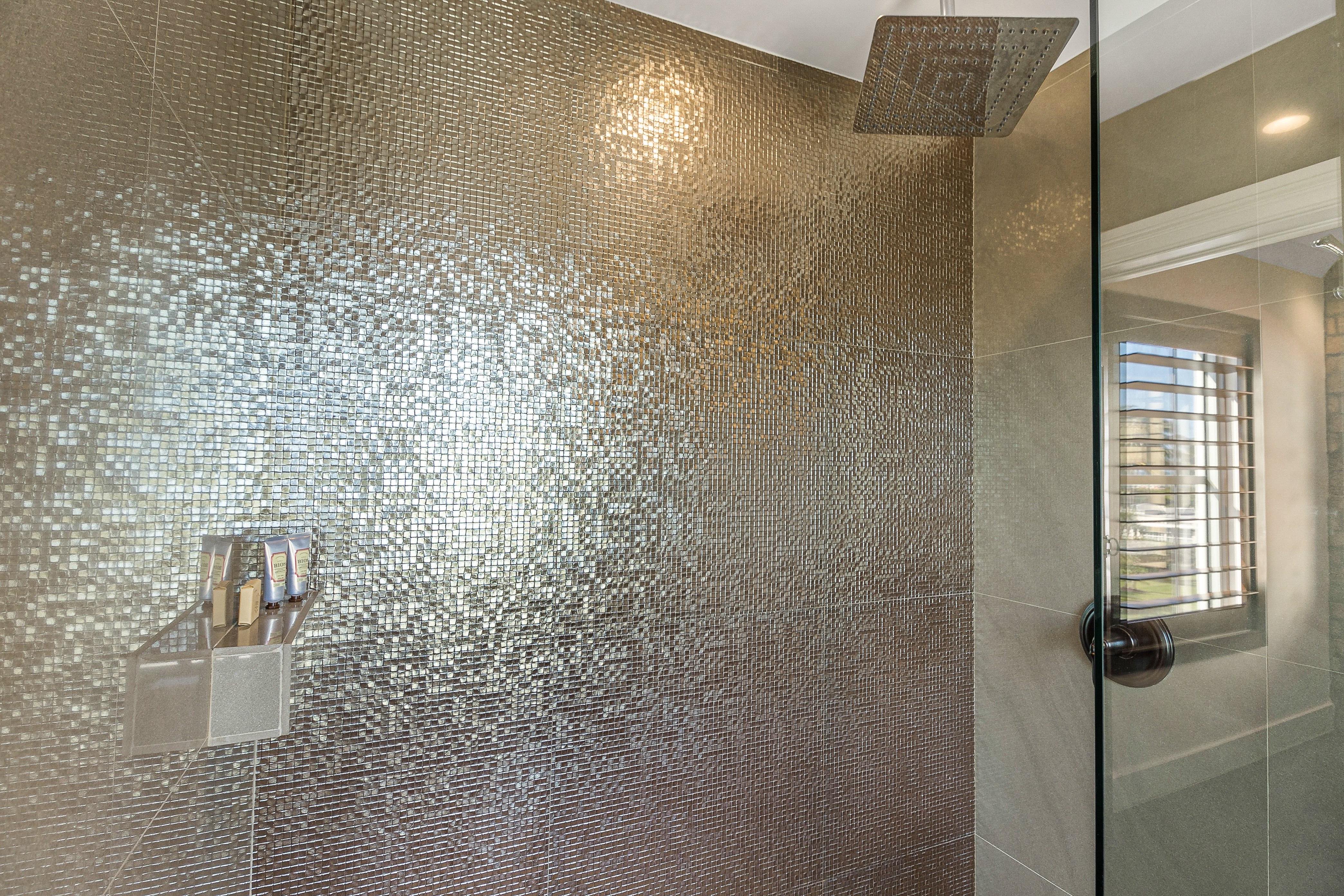 A shower with a tiled wall and a glass door