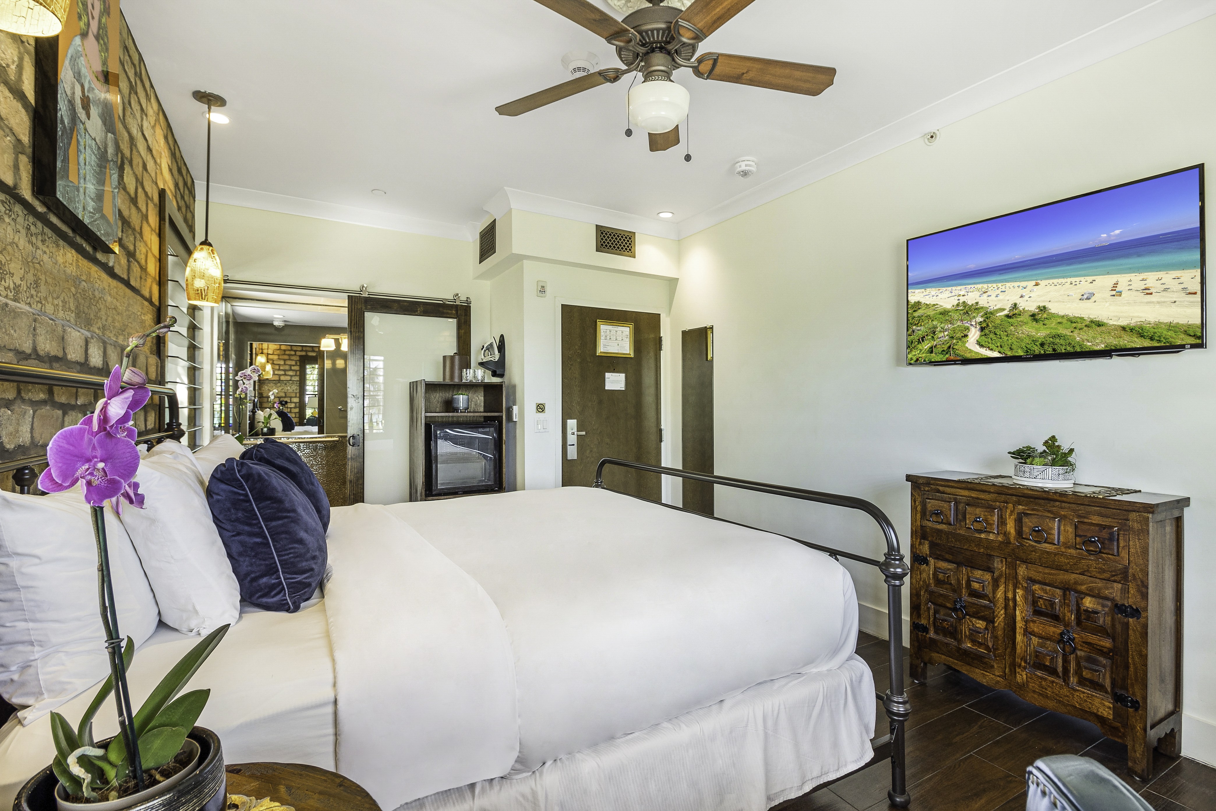A hotel room with a bed, TV, dresser, and ceiling fan.