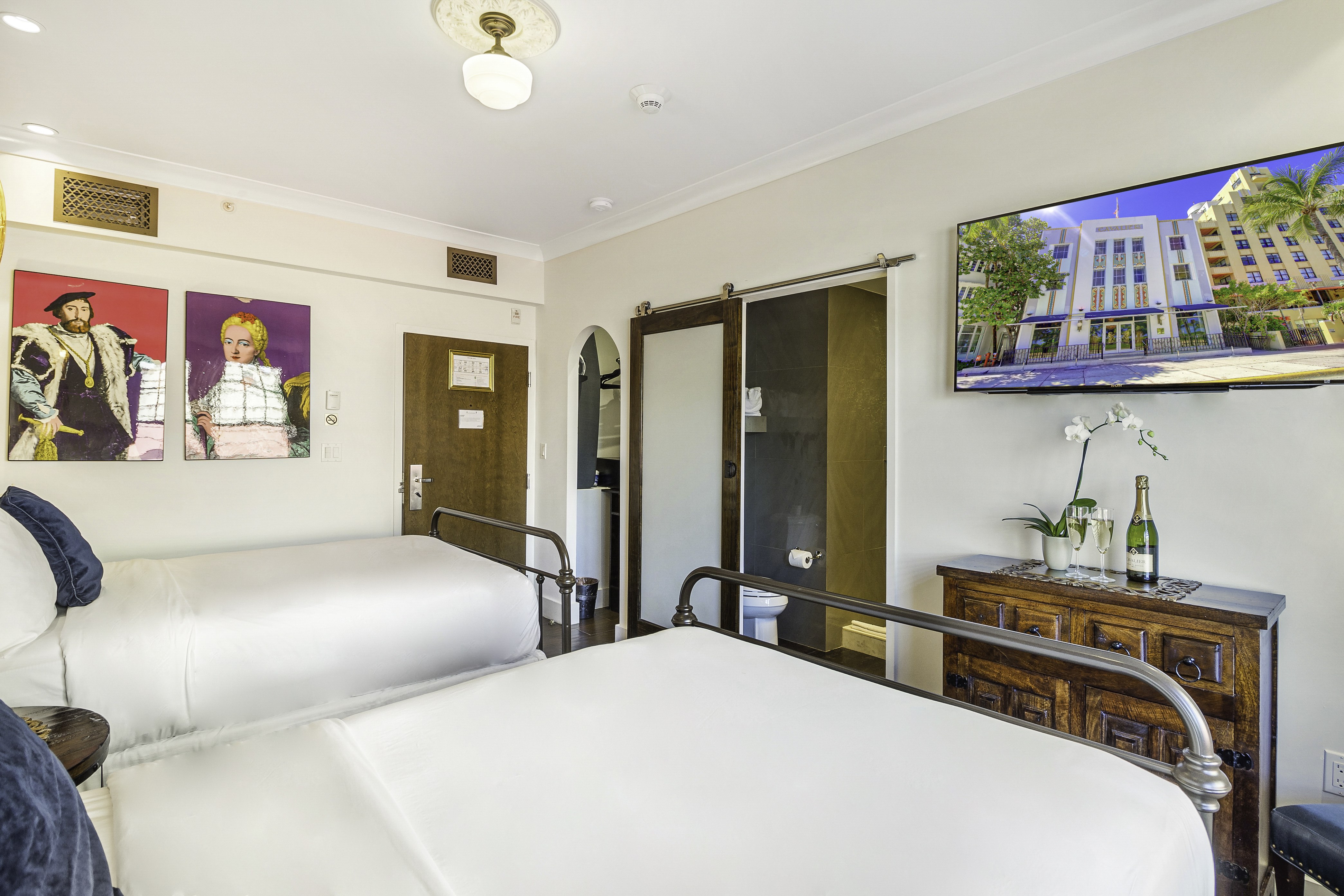 A hotel room with two beds, a TV, and a dresser.